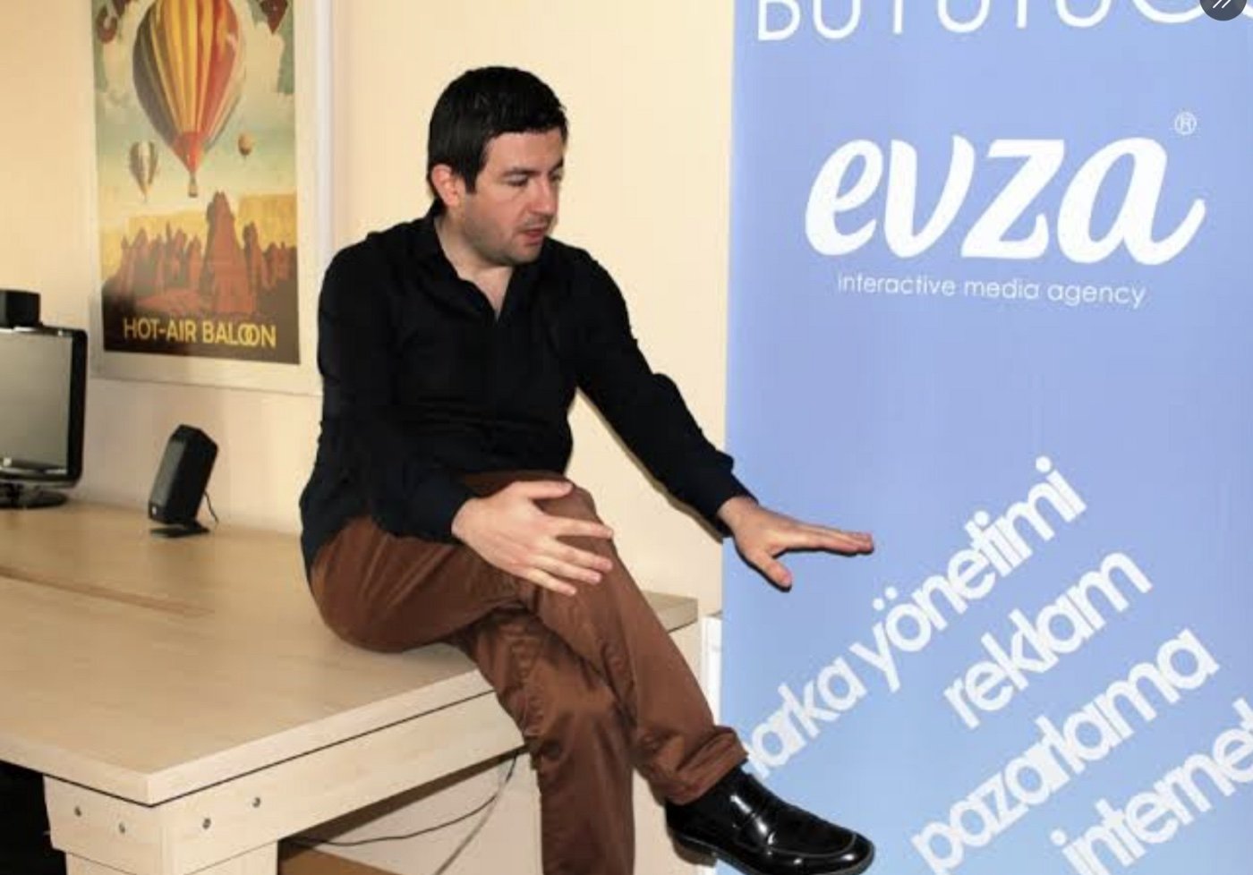 Ahmet Faruk Tuna at the Evza office, next to an Evza banner